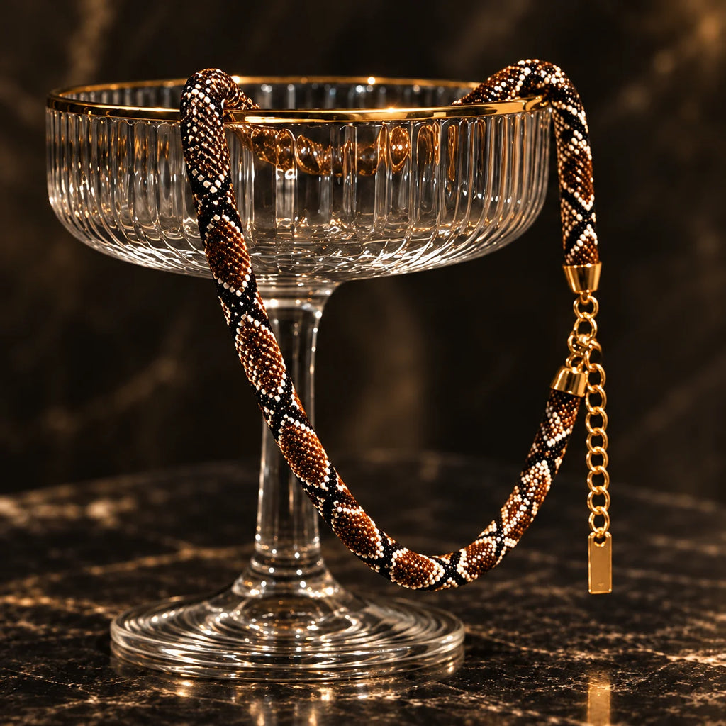 Serpent necklace draped over a glass